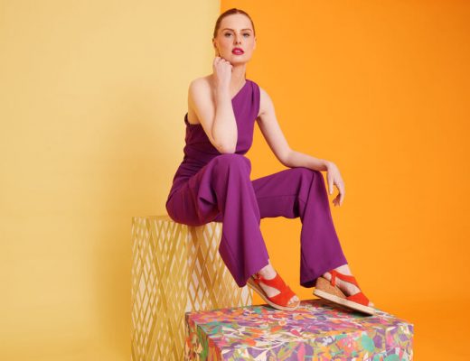 Woman in a purple jumpsuit wears orange wedge sandals